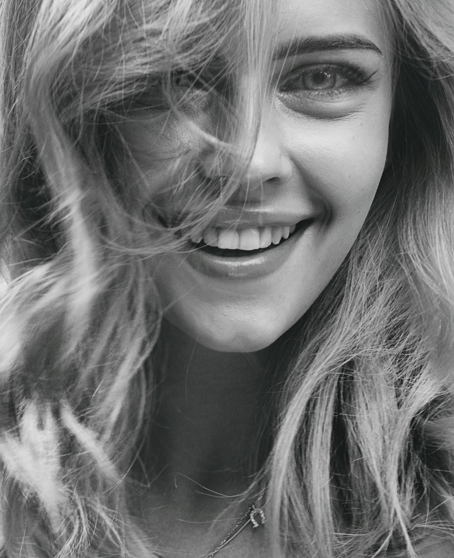 Black-and-white portrait of a woman laughing freely, teeth clearly visible